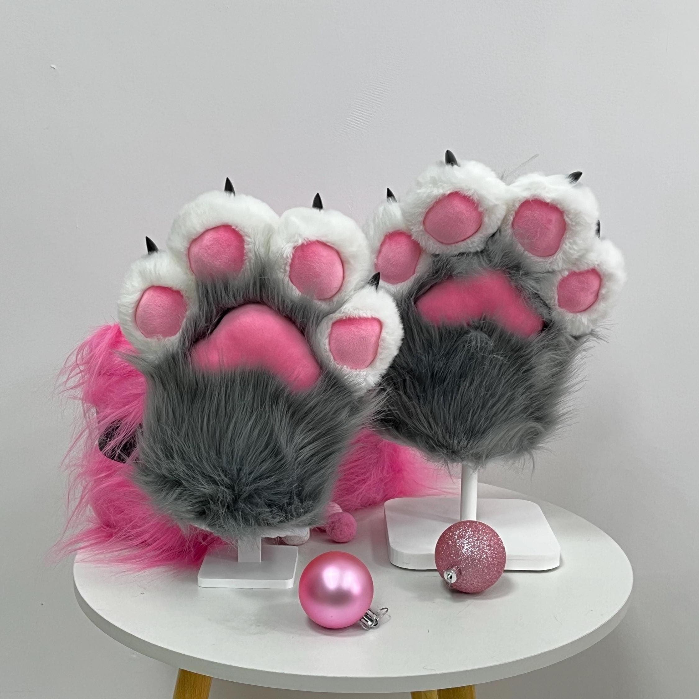 Classic wolf grey fursuit paws with white knuckle pads, sharp 3D sculpted dark claws and vibrant hot pink stuffed beans, displayed as a pair. These toony grey faux fur handpaws bring that feral husky, arctic wolf or werewolf vibe to any partial fursuit build. Premium soft long pile fiber, four finger cartoon mitten shape, one size fits most adult hands. Ideal for fur con debuts, Halloween parties, monster cosplay photoshoots and every fursona reveal at the next anime con.