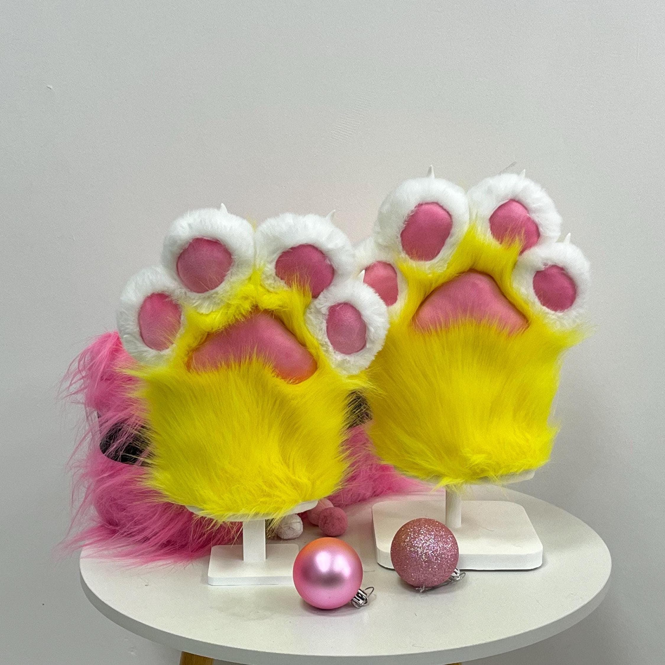 Electric lemon yellow furry handpaws pair with fluffy white fingertip pads and bright rose pink stuffed beans, standing on mini display plinths. These neon toony paws scream rave fursona, chibi fursuit partial or bright cheerful protogen build energy. Long pile soft faux fur, sculpted chunky silhouette, four finger cartoon mitten cut. One size fits most adult hands and feels super lightweight for long convention wear, dance floor shows, furry meetups and rave photoshoots.