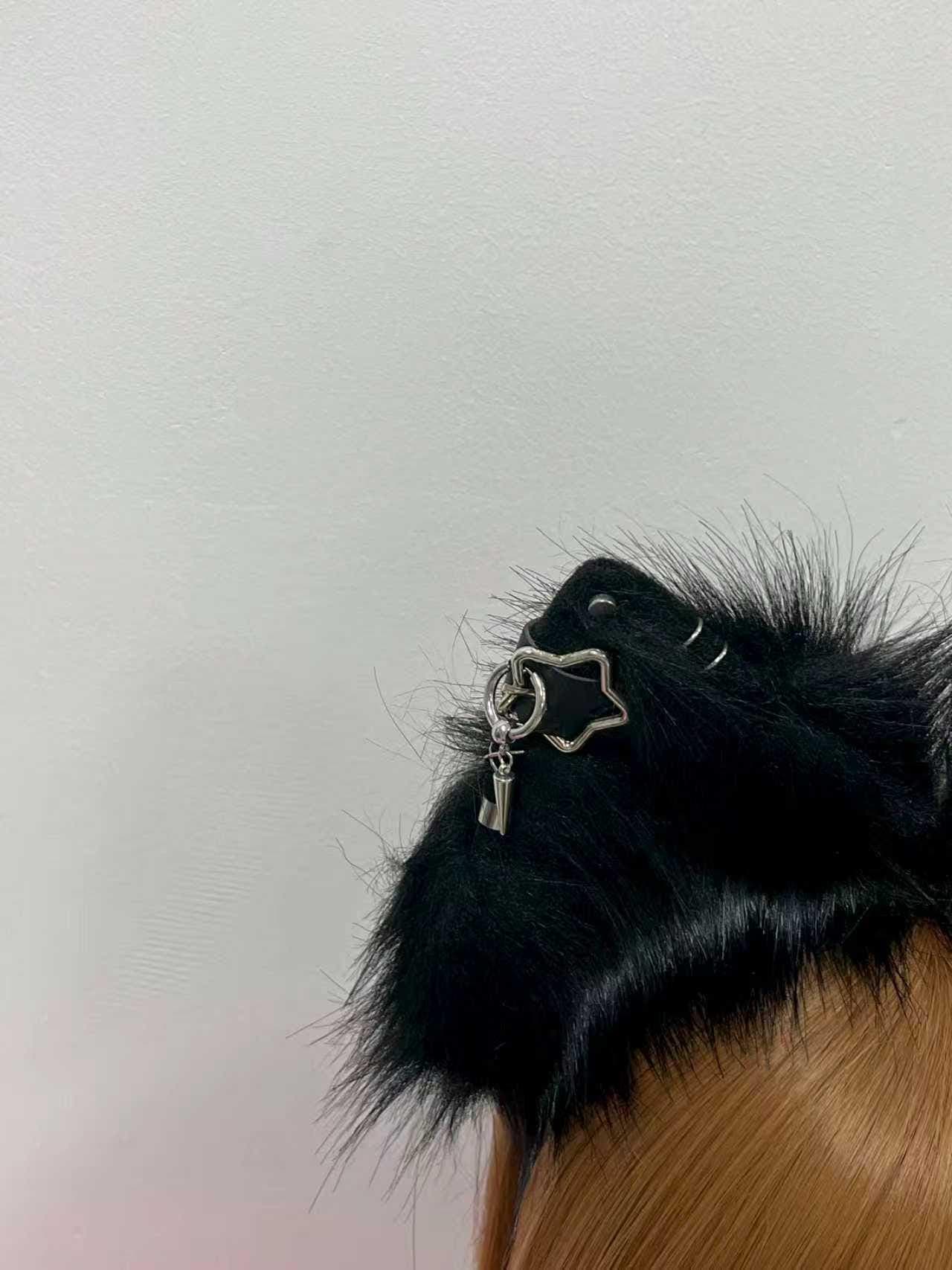 Macro close up of one black fox ear highlighting the silver star buckle piercing with dangling spike charm, small metal cuff, and tiny chain accent nestled in the thick raven fur. Shows individual strand detail and the hand stitched seam along the ear edge for collectors who care about craftsmanship. A unique find for punk catgirl lovers, cyberpunk wolf builds, metalhead alt fashion fans, and anyone wanting dimensional piercing hardware instead of flat printed decorations on fluffy animal ears.