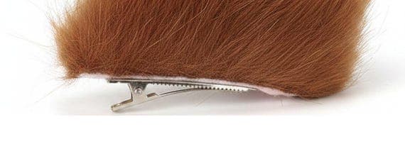 Fox ear hair clip close up detail showing silver alligator clip attachment at base of brown faux fur ear. Two angle views of single clip on fox ear showing metal hair clip mechanism. Clip on fox ear cosplay accessory detail view showing secure alligator clip attachment for easy wear