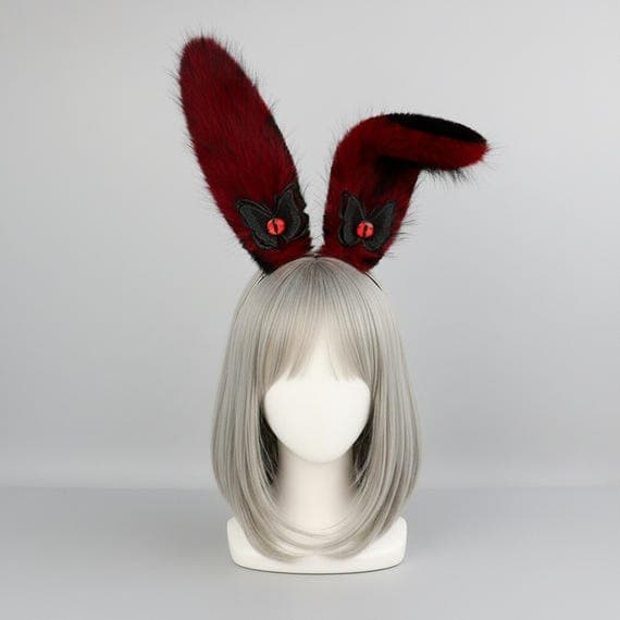 Devil eye bunny ears headband in red and black on mannequin head with dark brown wig, red plush faux fur rabbit ears with detailed embroidered reptilian devil eye and black wing accent at base, dark fantasy demon style rabbit ear hair accessory perfect for cosplay costumes anime conventions Halloween costume parties and gothic themed dress-up, evil eye bunny ear headpiece ideal for photo shoots festival outfits and edgy dark costume accessories for women teens and cosplay fans
