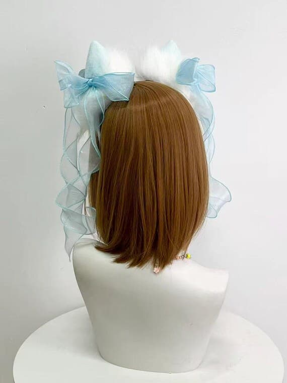 Back view white cat ears showing blue organza ribbons flowing down shoulders, creating ethereal fairy movement for lolita photography, conventions, costume photoshoots. Slim headband disappears into wigs and hair for seamless neko look. Ideal for sweet lolita coords, fairy kei, harajuku jfashion, kawaii anime cosplay, tea parties, magical girl costumes, maid cafe, pastel builds needing delicate feminine accessories for conventions and special occasions throughout the year and event season