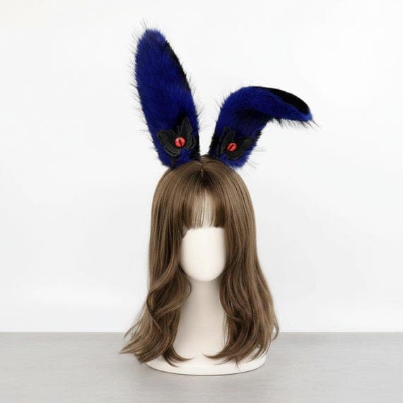 Devil eye bunny ears headband in blue and black on mannequin head with styled wig, blue plush faux fur rabbit ears with embroidered reptilian devil eye and black wing accent at base, dark fantasy demon style gothic rabbit ear hair accessory for cosplay costumes anime conventions Halloween costume parties and goth dress-up, evil eye bunny ear headpiece ideal for photo shoots festival outfits and edgy dark costume accessories for women teens and dark aesthetic cosplay fans
