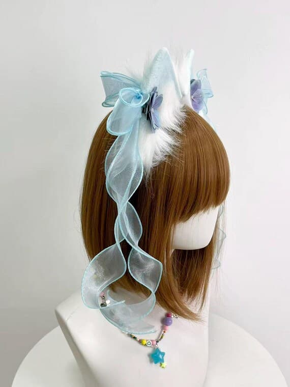 Side view white cat ears headband with flowing blue organza ribbons and purple flowers, realistic fluffy shape for fairy kei lolita and kawaii neko cosplay. Lightweight headband stays secure during conventions, photoshoots, tea parties. Handmade faux fur ears with feminine aesthetic for pastel goth, sweet lolita, fairy tale cosplay, harajuku fashion, jfashion outfits, cute gifts for anime fans, cosplayers, and kawaii accessory collectors who love quality costume pieces for conventions and specia