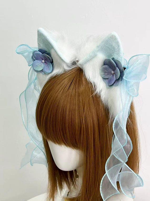 Close-up detail of blue organza ribbons and purple hydrangea on white cat ear headband, showing premium craftsmanship and fairy lolita aesthetic. Cascading ribbons add movement to neko cosplay, perfect for tea party coords, garden outfits, fairy kei fashion, sweet lolita style, kawaii conventions, romantic builds. High-quality synthetic materials are cruelty-free, durable, designed for anime cons, photoshoots, special events, and cosplay meetups year-round with comfortable all-day wear