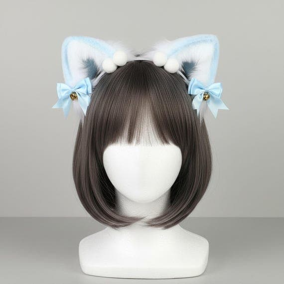 Plush blue faux fur cat ear headband with white fluffy inner ears white pompom tufts at crown blue satin ribbon bows and gold jingle bells on a mannequin head with dark brown bob wig, plush cat ears cosplay neko ears lolita anime kawaii headband cat ears with bells fluffy ears cute cat ears kitten ears faux fur cat ears kawaii accessories gift for cat lover anime cat ears against neutral grey studio background